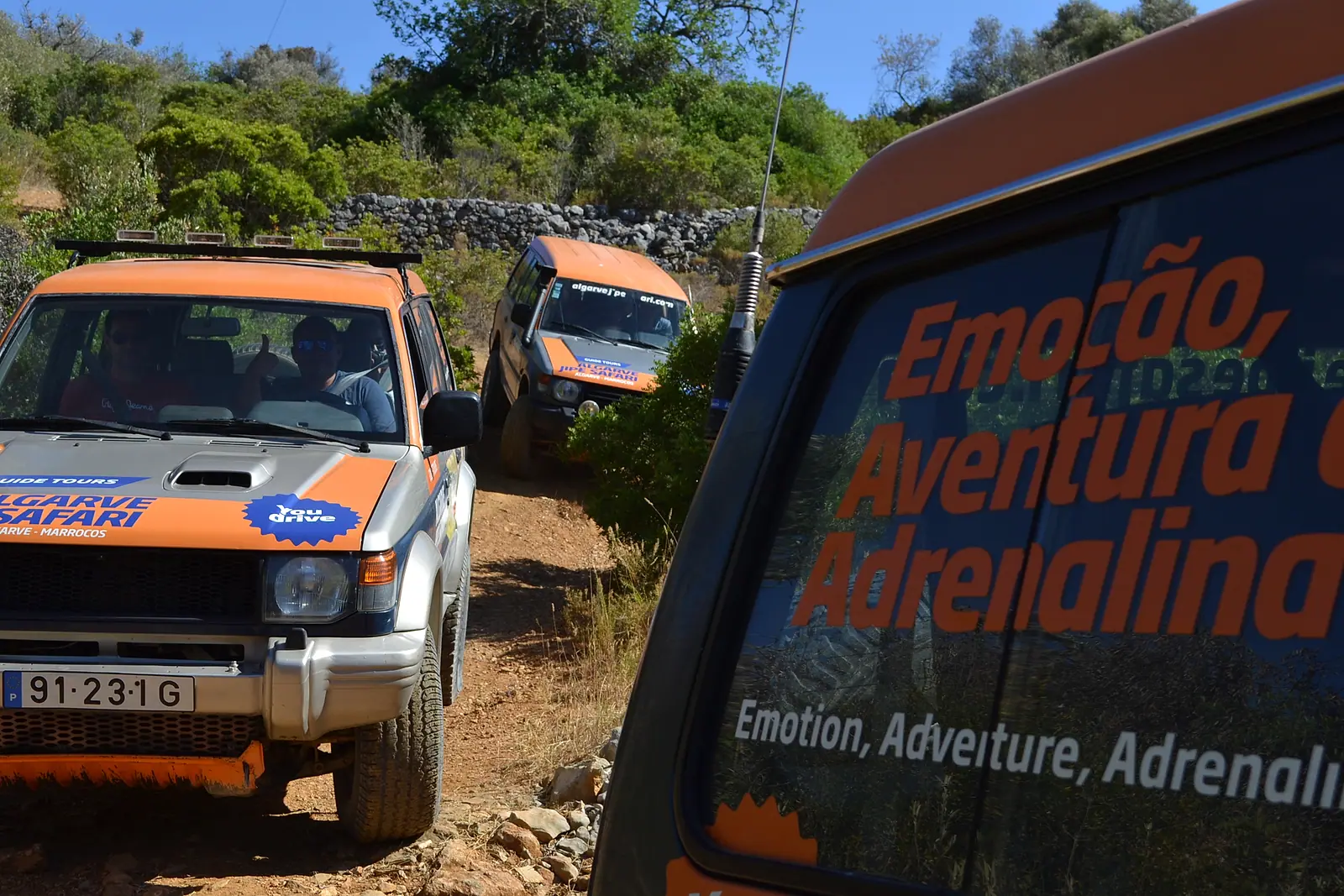 A convoy of orange jeeps on a wooded trail