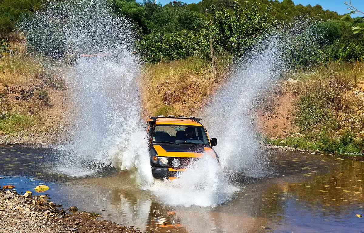 Orange jeep crossing water on an off-road trail